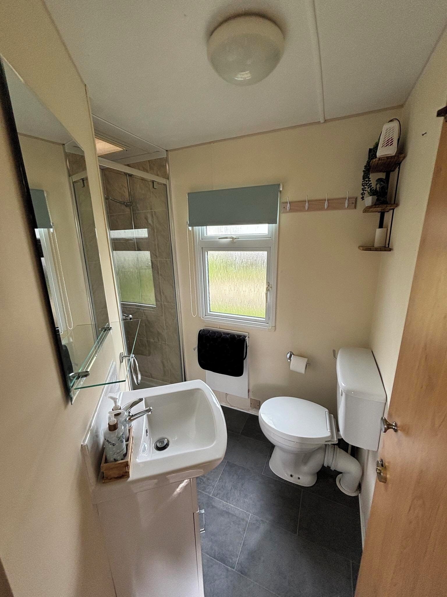 A compact bathroom with a sink, toilet, and a small window.