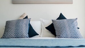 A bed with patterned pillows and a painting of a beach scene above it. - Spectacular Sea View Penthouse Apartment + Parking (Newquay)