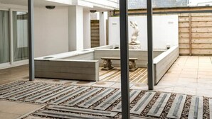 Een ruim terras met een zwembad, stenen banken en een standbeeld.