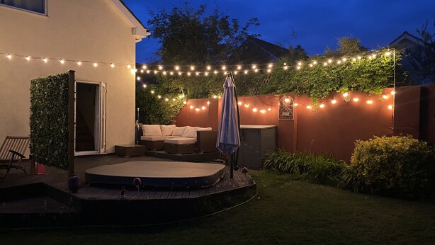 A backyard with a hot tub, string lights, and a covered seating area. - 3 Bedroom House, Hot Tub,torbay, Sleeps 6, Parking (Newton Abbot)