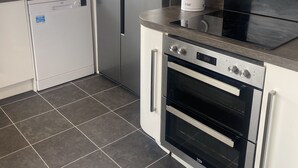 A modern kitchen with a dishwasher, a refrigerator, a kettle, and an oven. - 3 Bedroom House, Hot Tub,torbay, Sleeps 6, Parking (Newton Abbot)