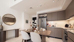 A modern kitchen with built-in appliances, a dining area with a round table and chairs, and a large mirror on the wall.