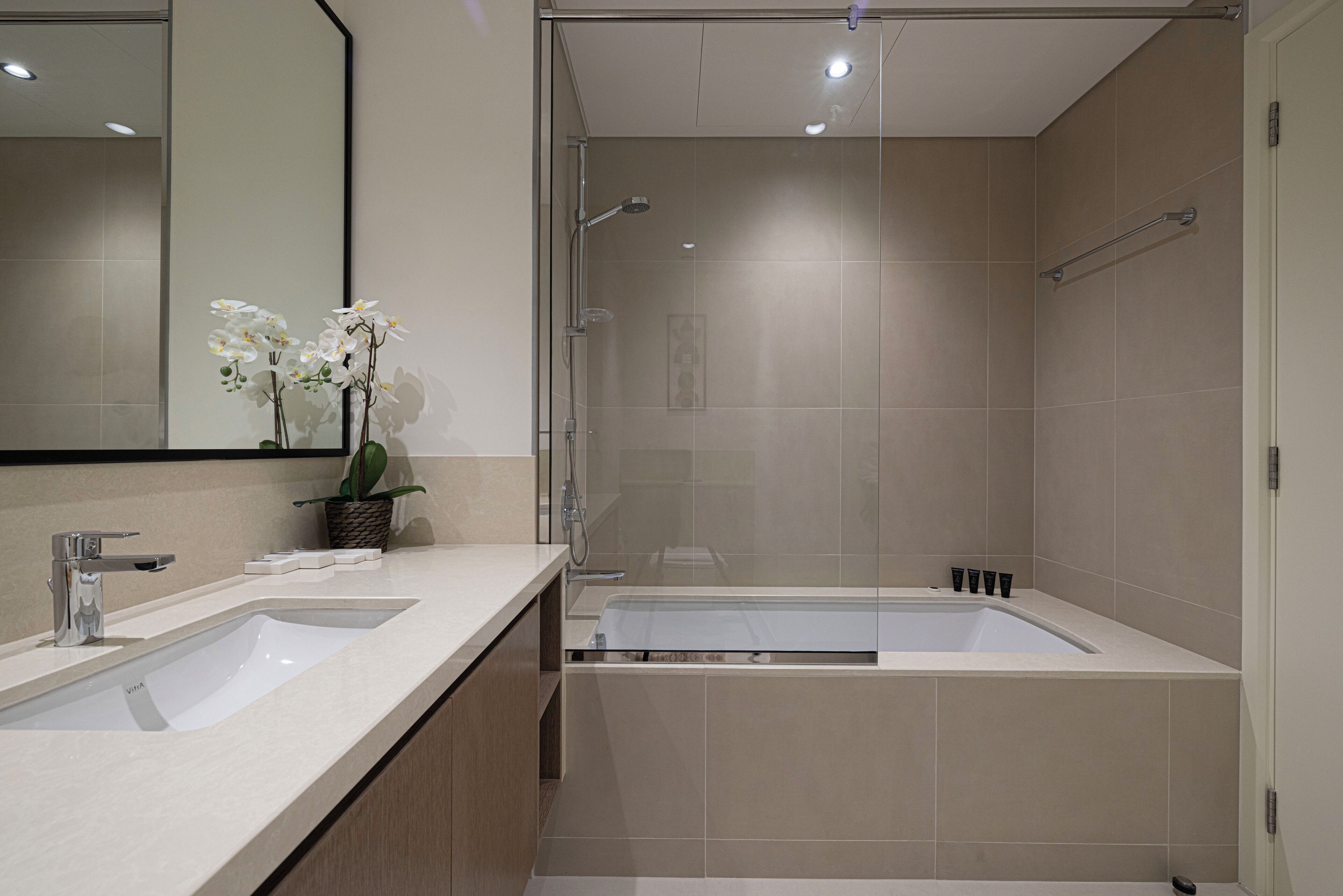 A modern bathroom with a large sink, a bathtub, and a glass shower enclosure.