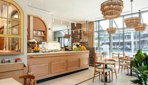 A modern cafe with a wooden counter, seating area, and large windows offering a view of the street. - First Class Burj Khalifa Views (Dubai)