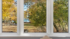 A window with three panes, each offering a view of a park with trees and a playground. - Lower Terrace in Three Pines Resort (Frankfort)