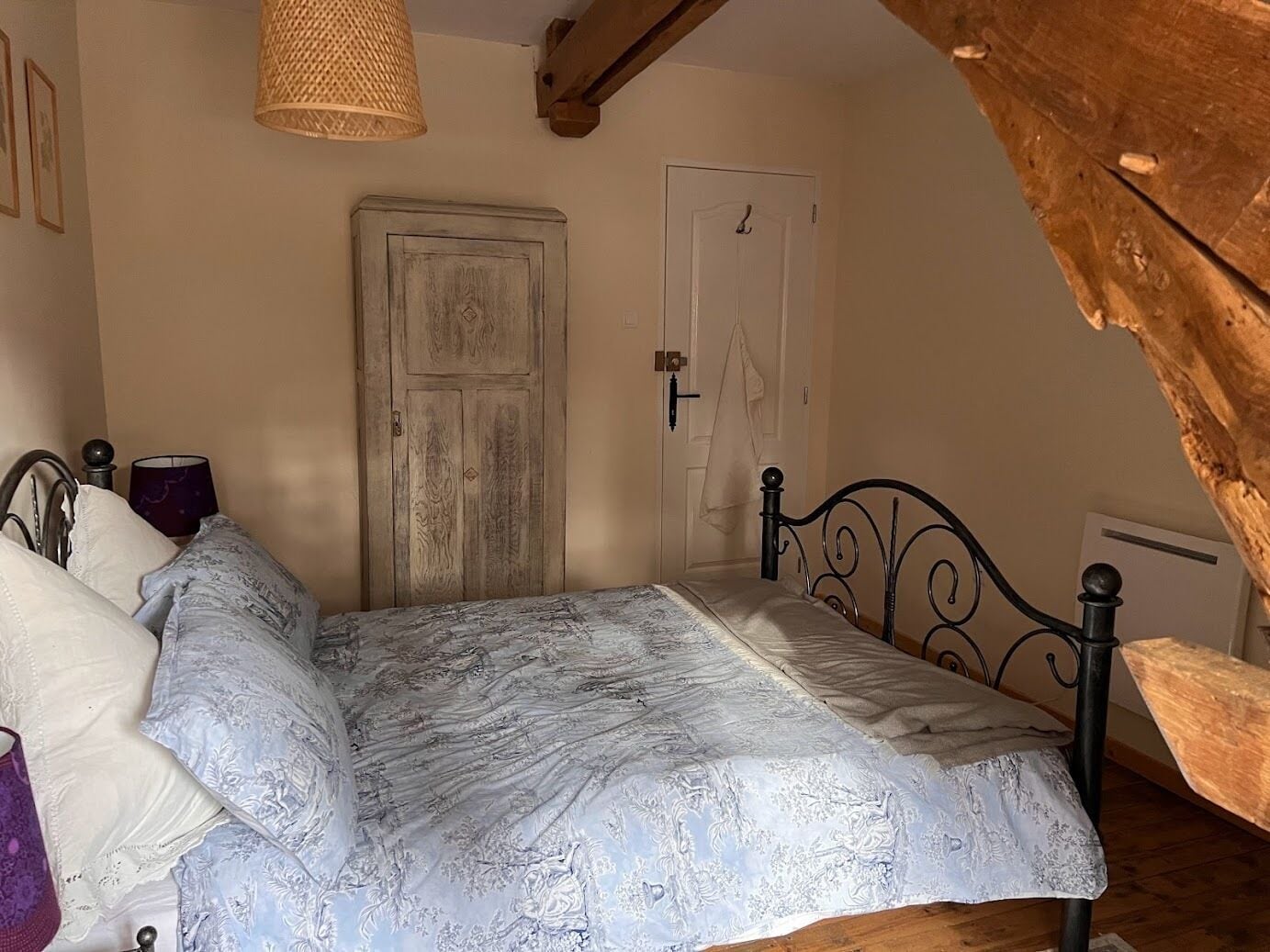 A bedroom with a bed, a wooden door, and a sloped ceiling.