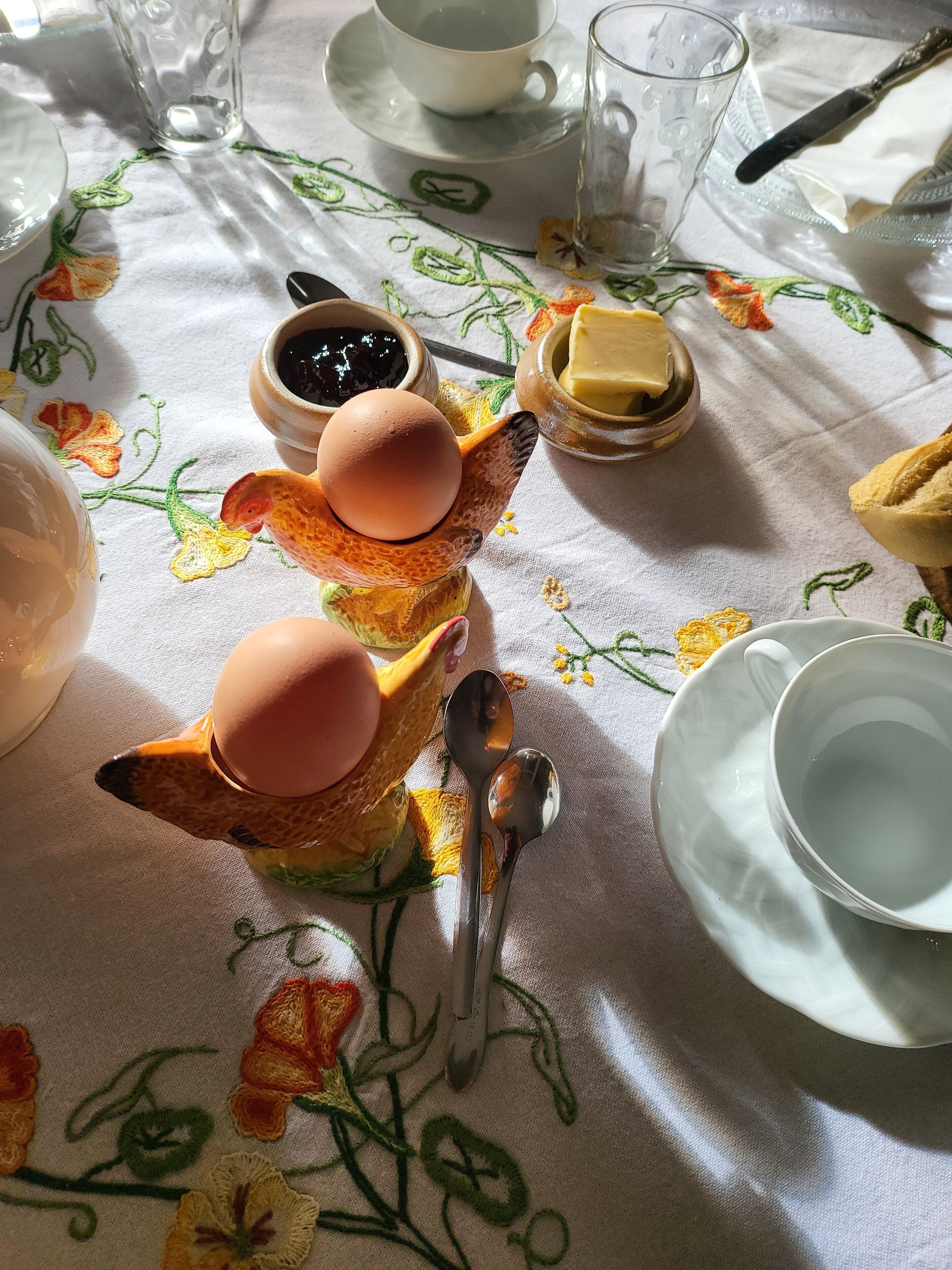 A table set with a ceramic fox figurine holding eggs, a glass of water, a cup, a butter dish, and a plate.