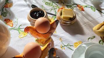 A table set with a ceramic fox figurine holding eggs, a glass of water, a cup, a butter dish, and a plate.