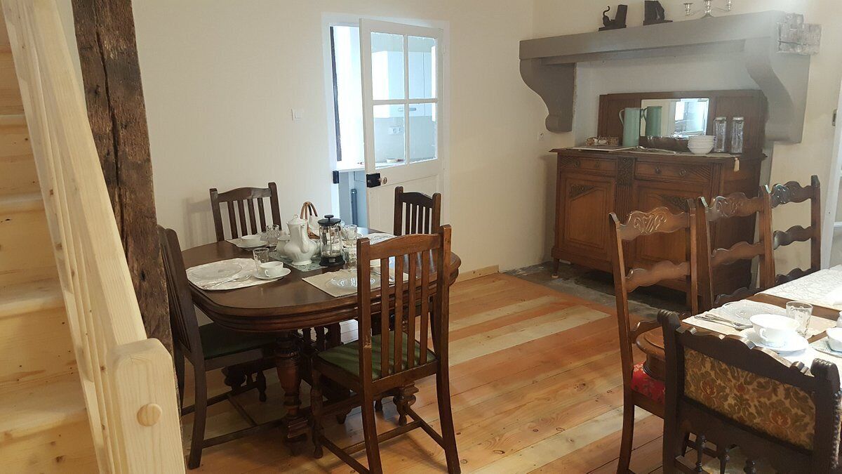 Un comedor con mesa y sillas de madera, una ventana y una encimera de cocina con armarios.