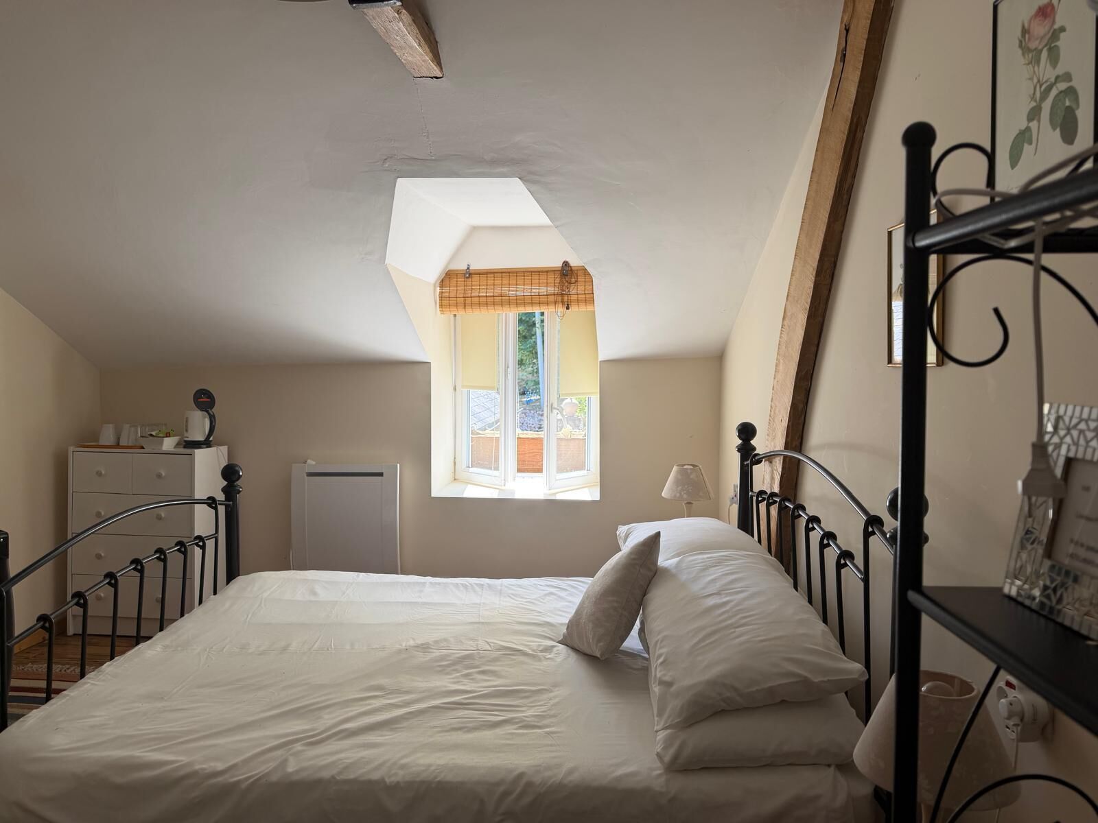 A bedroom with a bed, a window with a view, a desk, and a radiator.