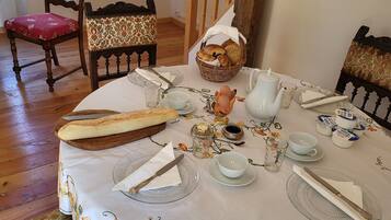 Une table à manger dressée avec des assiettes, des couverts, un panier de pain et une carafe.