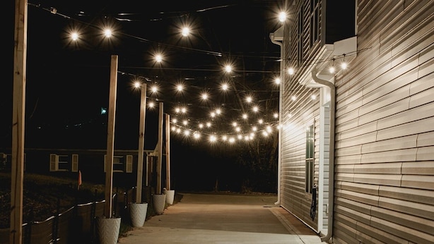 A pathway leading to a building with string lights overhead.