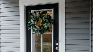 A front door with a wreath, a doormat, and a mailbox.