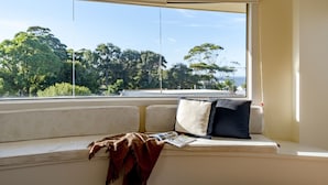 A window seat with a cushion, a blanket, and a magazine. - Anchors at Mollymook Beach (Mollymook)