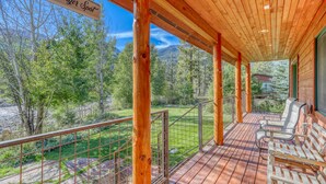 A wooden deck with a sign reading "Gold Garden Burger Spot," overlooking a grassy area with trees and a mountain in the background.