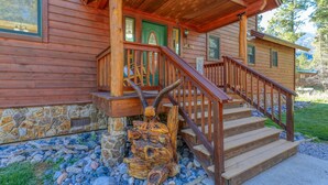 A wooden cabin with a stone foundation, a wooden staircase, and a welcome sign.