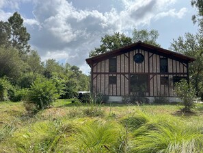 A traditional timber-framed building with a symmetrical facade, large windows, and a central circular window. - Vrbo Property (Lévignacq)
