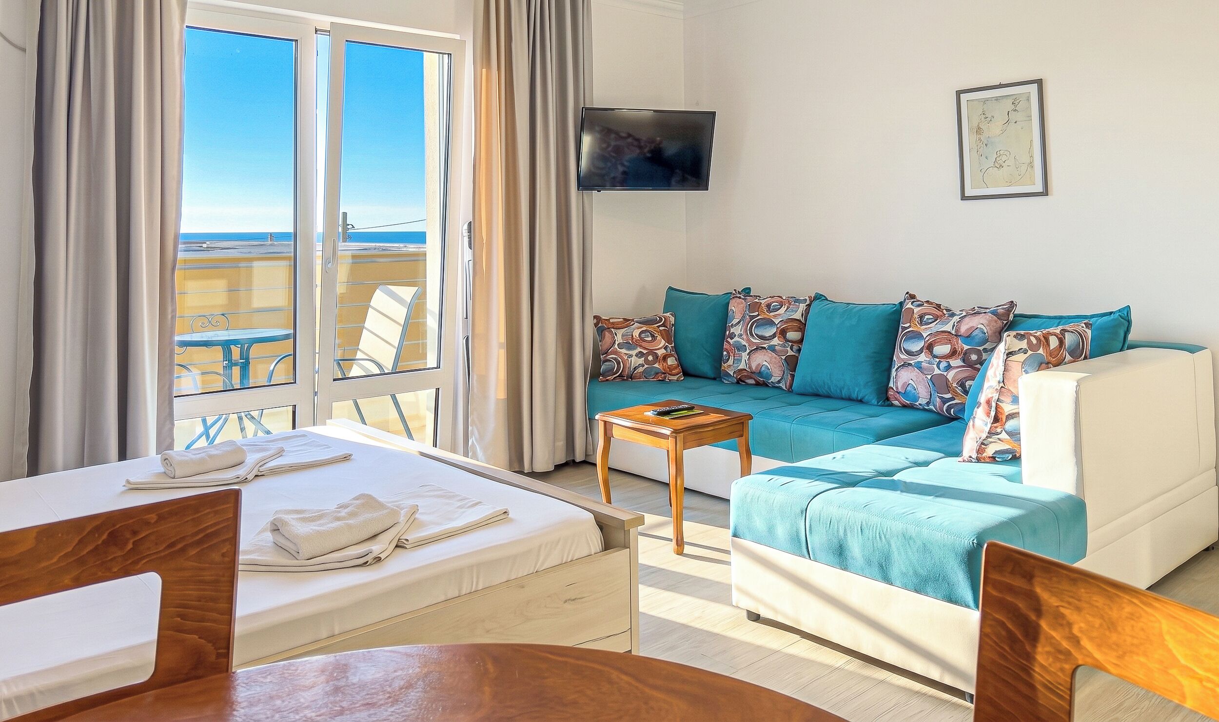 Ein Zimmer mit Bett, Sofa, Fernseher und Meerblick.