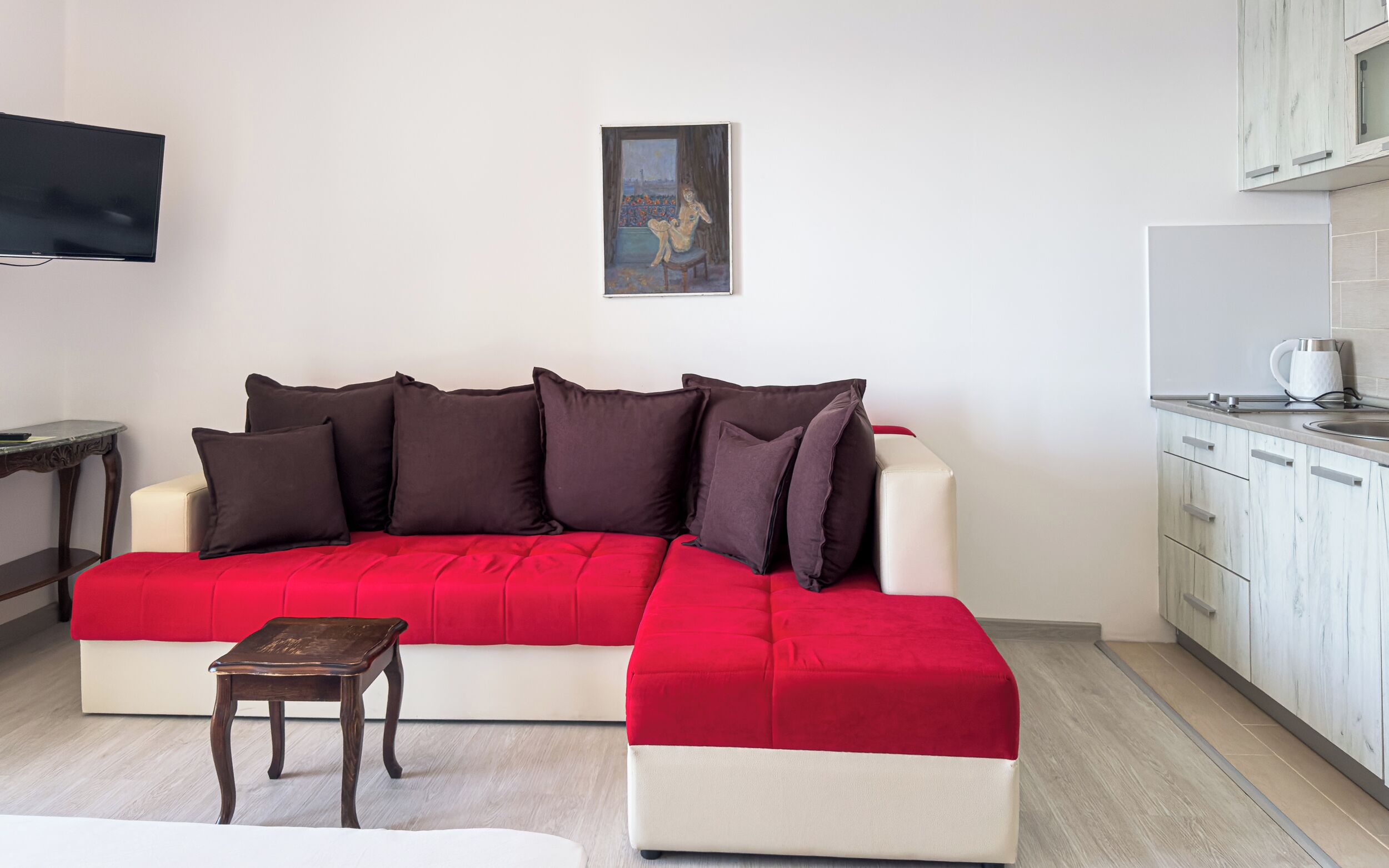 En moderne stue med en rød sofa, et lille træbord og et billede på væggen.