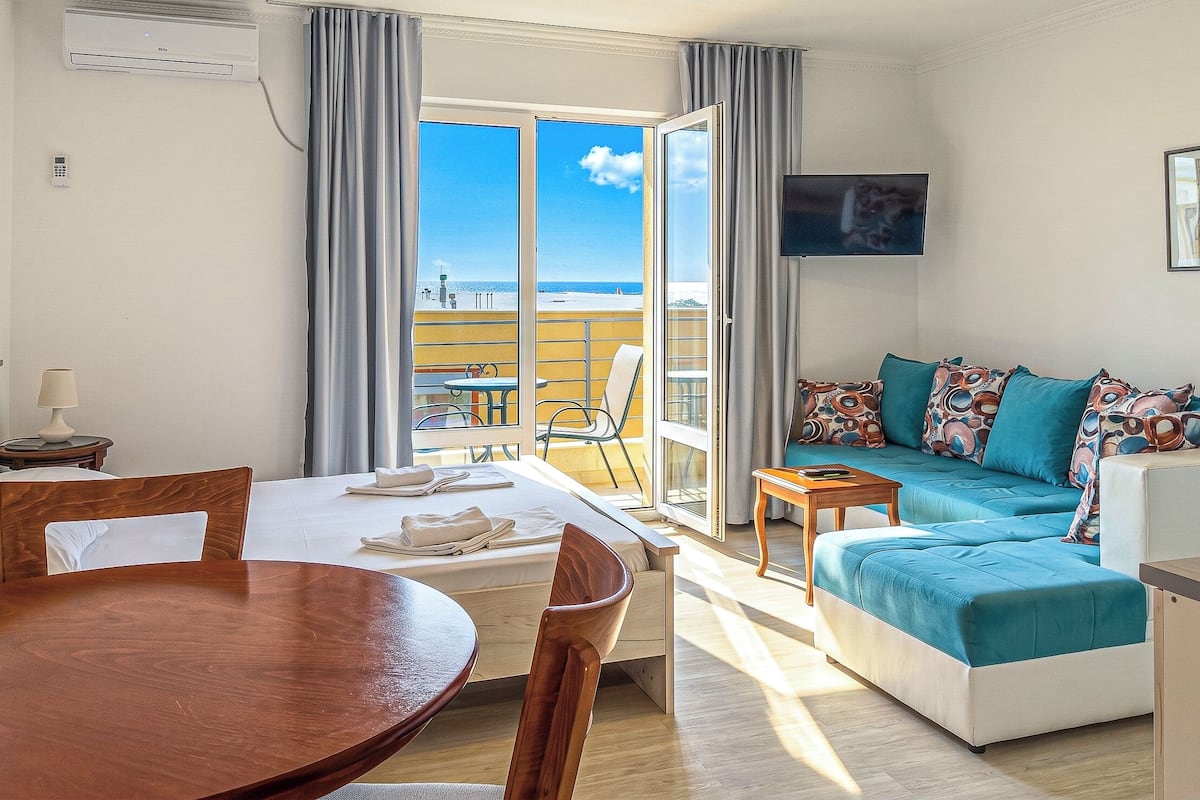 A room with a bed, a sofa, a table, and a TV.
