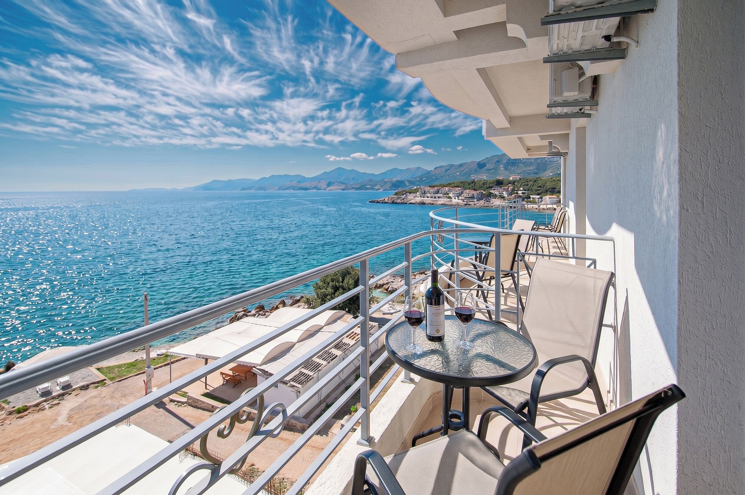 A balcony with a table, chairs, and a bottle of wine.