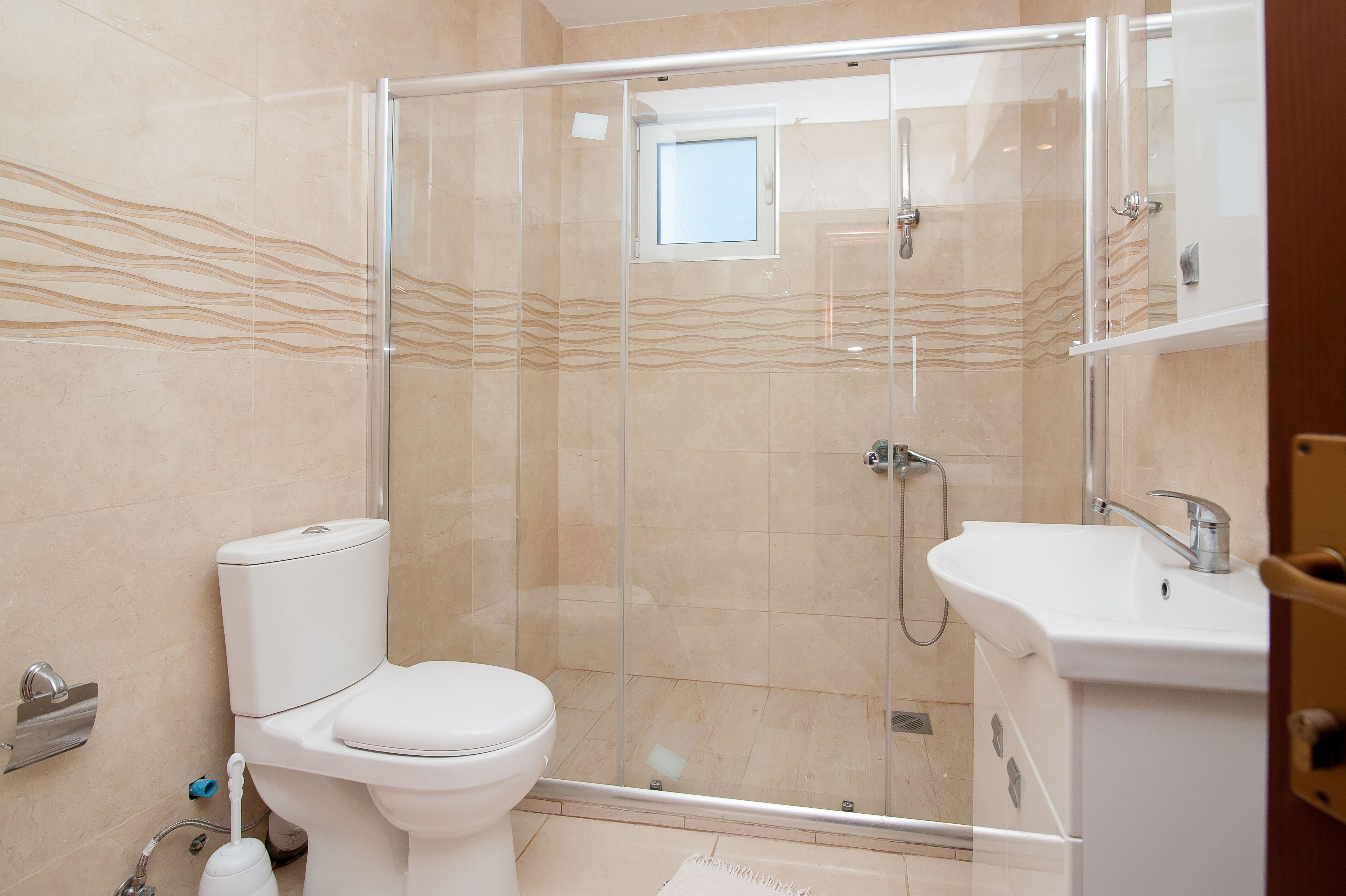 A modern bathroom with a glass-enclosed shower, a toilet, and a sink.
