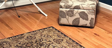Ein Zimmer mit einem gemusterten Sessel, einem kleinen Tisch mit einem Bügeleisen und einem dekorativen Teppich.