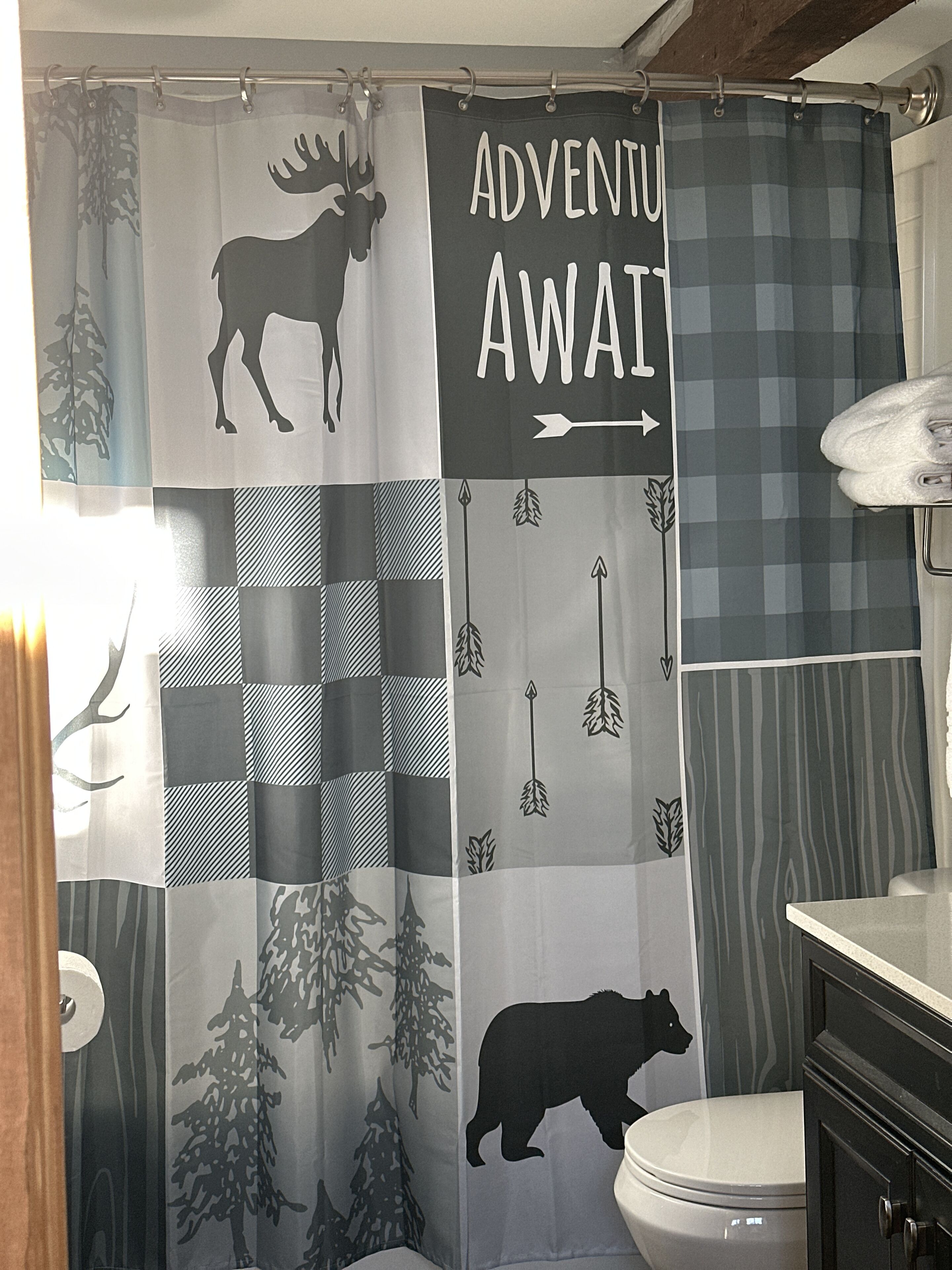 Un bagno con tenda da doccia decorata con stampe di animali selvatici e il testo "ADVENTU AWAI".