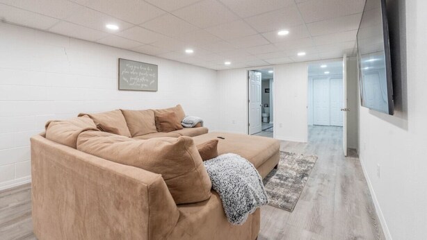A modern living room with a beige sectional sofa, a flat-screen TV mounted on the wall, and a framed inspirational quote on the wall. - A Home away from Home (Waterloo)