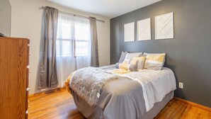 A bedroom with a bed, curtains, a wooden wardrobe, and three wall-mounted picture frames. - A Home away from Home (Waterloo)