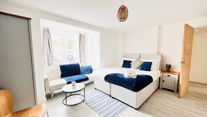 Een moderne hotelkamer met een bed, een bank, een klein tafeltje en een nachtkastje.