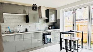 Een moderne keuken met een inbouwoven, een spoelbak en een eethoek met een tafel en stoelen.