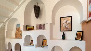 Una galería con obras de arte y objetos decorativos exhibidos en estantes blancos con arcos.