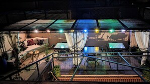 Un área exterior con mesas y sillas, un sofá y una escalera.