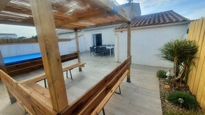 Un espace extérieur aménagé en terrasse, avec des bancs en bois, une table à manger et des chaises.