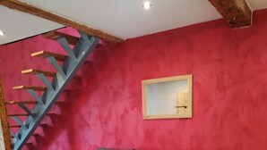 Una sala moderna con un sofá seccional gris, dos mesitas de madera y una pared de acento roja.