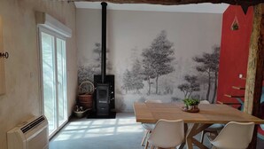 Un comedor con una mesa, sillas, una chimenea y un mural de árboles.