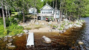 Una cabaña con un muelle que se adentra en un río rodeado de árboles.