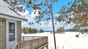 Una casa con terraza de madera y patio cubierto de nieve.