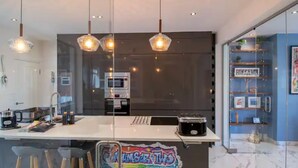 A modern kitchen with a central island, stainless steel appliances, and pendant lighting.