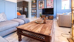 A modern living room with a grey sofa, a wooden coffee table, and a TV on a wooden stand.