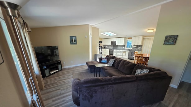 A living room with a brown sofa, a TV, and a dining area with a table and chairs. - Fisherman Friendly and minutes from the beach (Rockaway Beach)