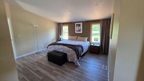 Un dormitorio con cama, mesita de noche, lámpara, ventana con cortinas y lámpara de pie.