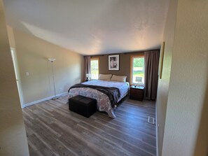 A bedroom with a bed, a bedside table, a lamp, a window with curtains, and a floor lamp.