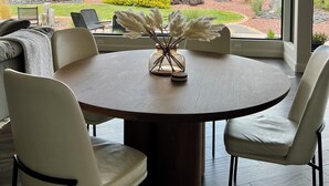 A dining area with a round table, white chairs, and a vase with pampas grass. - Luxury 4-bedroom Retreat- stellar red rock views – St. George's Premier Getaway (Ivins)