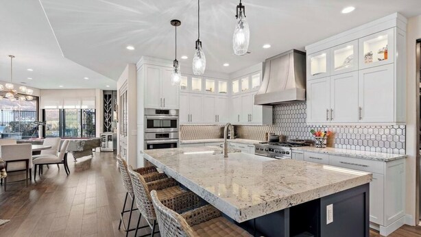 A modern kitchen with white cabinetry, a large island with bar stools, and pendant lighting. - Luxury 4-bedroom Retreat- stellar red rock views – St. George's Premier Getaway (Ivins)