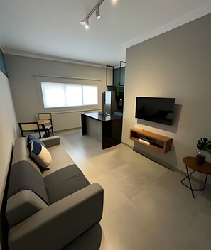 Relax in this stylish living room with a large flat-screen TV, comfortable sofa, and a side table.
