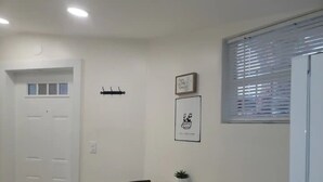 A small dining area with a round table and two chairs, a potted plant, and a framed picture on the wall.