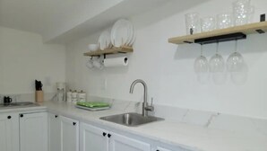 A kitchen with white cabinets, a stainless steel sink, and a marble countertop.
