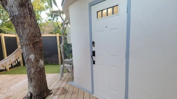 A wooden deck with a white door, a hammock, and a chair.